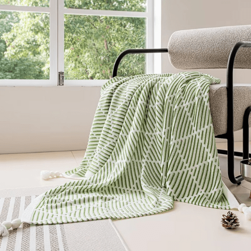 plaid décoratif à pompon vert placer sur un canapé